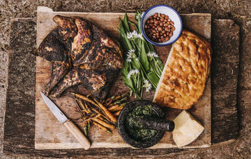 A barbecued, whole, properly free range spatchcock chicken with herbs, bread, carrots and cheese