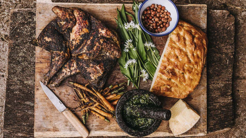A barbecued, whole, properly free range spatchcock chicken with herbs, bread, carrots and cheese