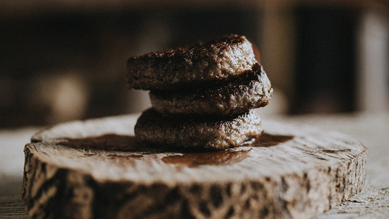 A stack of three cooked Grass fed beef steak burgers.