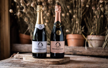 Two bottles of Swanaford sparkling wine standing on a chopping board.
