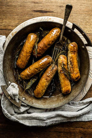 A pan of cooked, natural, native breed pork Cumberland sausages.