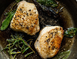 Properly free range turkey breast steaks cooking in a pan with sage and rosemary