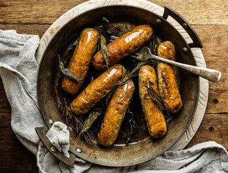 A pan of cooked, natural, native breed pork Cumberland sausages.