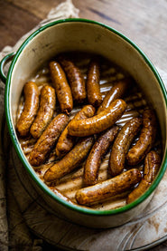 A pan of cooked natural, native breed pork and apple sausages.