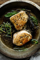 Properly free range turkey breast steaks cooking in a pan with sage and rosemary
