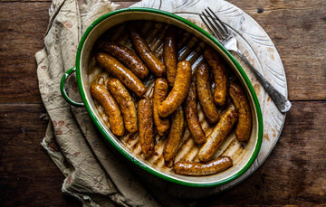 A pan of cooked natural, native breed pork and apple sausages.