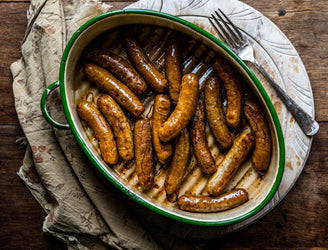 A pan of cooked natural, native breed pork and apple sausages.